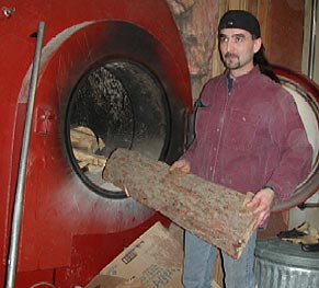 Man loading log into wood fired boiler